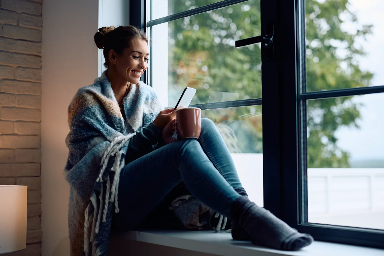 A person sitting quietly alone with a coffee by a window in soft morning light