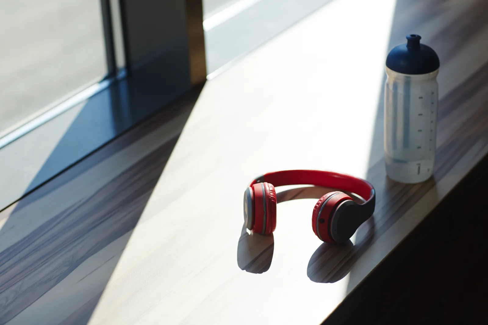 Headphones resting on a wooden table beside a window with warm morning light