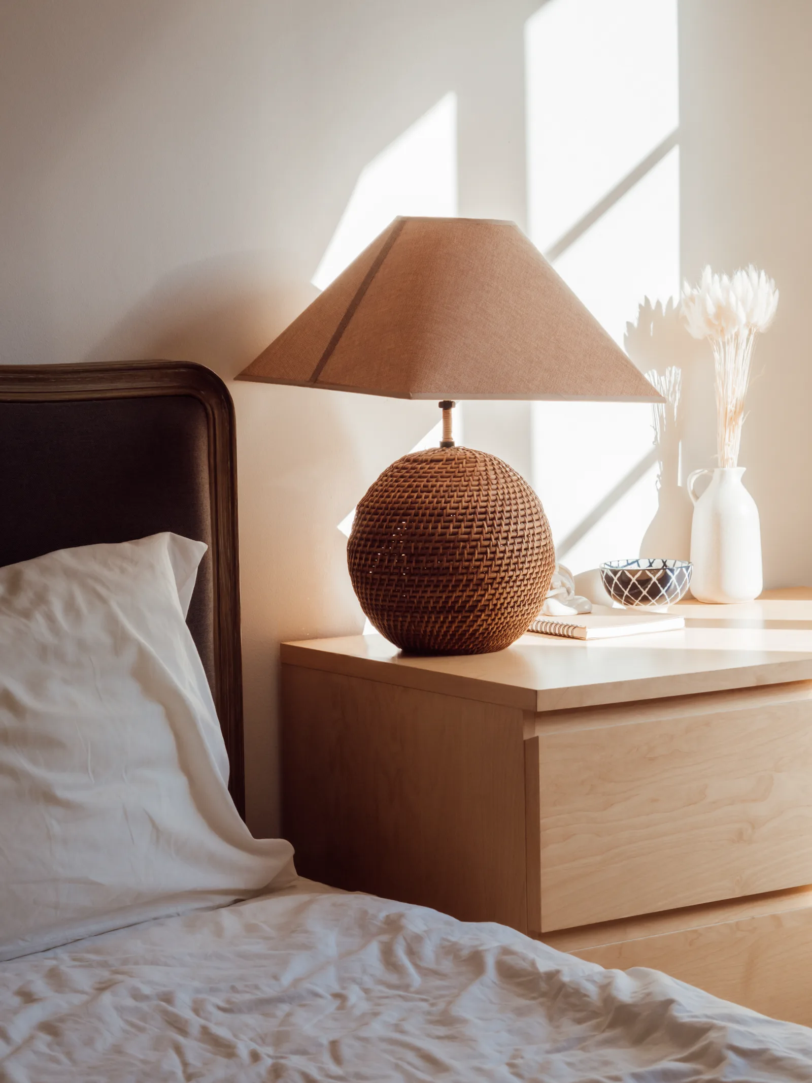 Soft natural morning light falling across a bedside lamp and nightstand